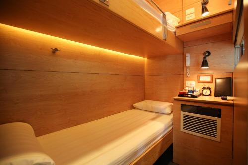 Habitación pequeña con cama y TV. en VATC Sleep Pod Terminal 2 en Noi Bai