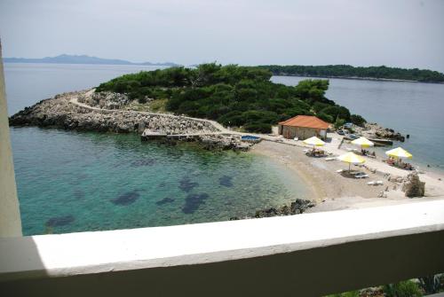 an island in the water with umbrellas and a beach at Hotel Priscapac Resort & Apartments in Prizba