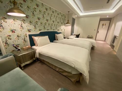 two beds in a room with floral wallpaper at U-Her Hotel in Taichung