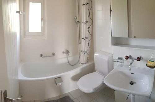 a white bathroom with a toilet and a sink at HSH Weber - 2 Bedroom Suite Apartment with Office, Salon and Kitchen in Bern by HSH Hotel Serviced Home in Bern