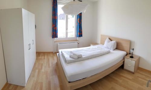 a bedroom with a bed with white sheets and a window at HSH Weber - 2 Bedroom Suite Apartment with Office, Salon and Kitchen in Bern by HSH Hotel Serviced Home in Bern