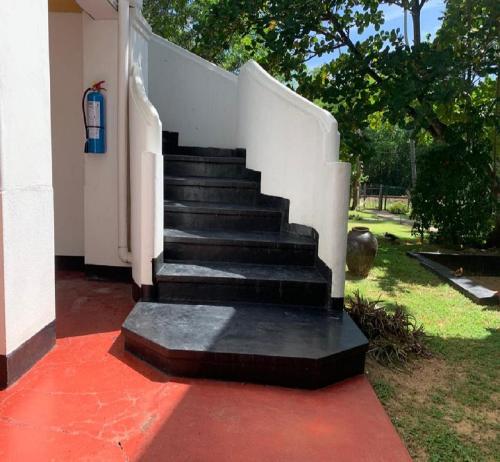 a staircase leading up to a house with a white wall at Palm Beach Inn & Sea Shells Cabanas in Bentota