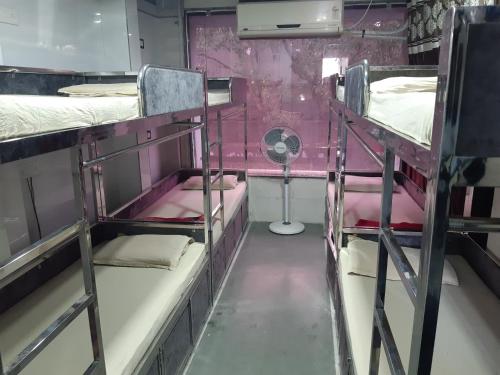 a room with three bunk beds and a fan at Shree Mahakali Guest House & Dormitory in Ahmedabad
