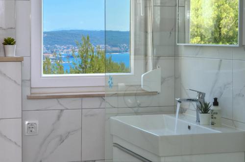 baño blanco con lavabo y ventana en Apartment Elza en Trogir
