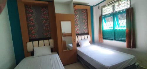 2 Betten in einem Zimmer mit 2 Fenstern und einem Spiegel in der Unterkunft Rumah Dempo Syariah in Sungaidurian