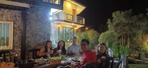 a group of people sitting at a table at night at Heuan Na Khee in Udon Thani