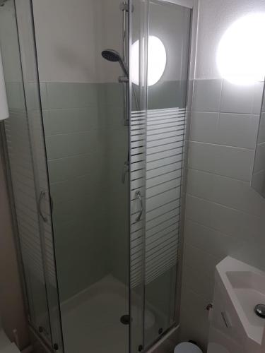 une douche avec une porte vitrée dans une salle de bain dans l'établissement T2 Bandol idéal vacances 2 étoiles, à Bandol