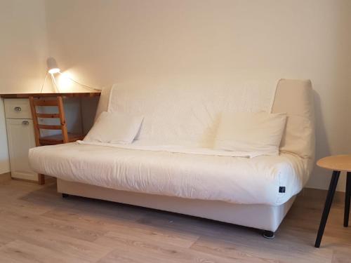 un lit blanc dans une chambre avec une table et une lampe dans l'établissement T2 Bandol idéal vacances 2 étoiles, à Bandol