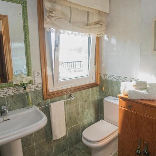a bathroom with a toilet and a sink and a window at Atico con vistas a la Lanzada in A Lanzada