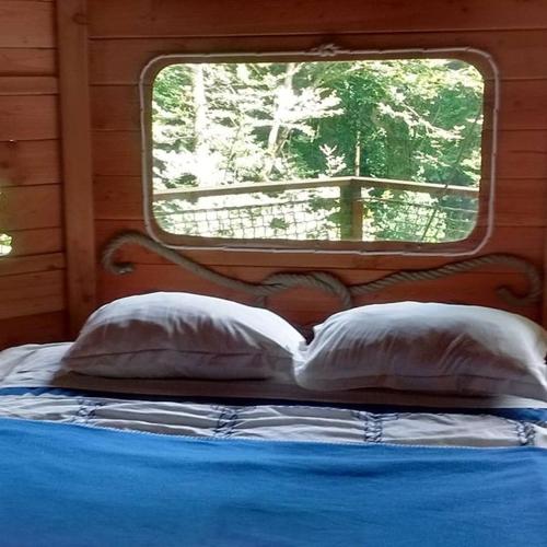 un lit dans une chambre avec une fenêtre dans l'établissement Les cabanes de Kermenguy, à Cléder