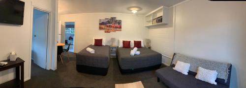 a living room with two couches and a television at Racecourse Motel in Paeroa
