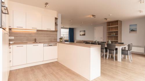 a kitchen with white cabinets and a table with chairs at Holiday Suites Blankenberge in Blankenberge