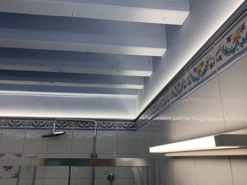 a kitchen with white walls and a ceiling with lights at Princess Art Hotel in Ferrara