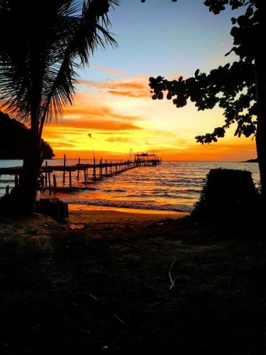 a sunset over the ocean with a pier at Kuba Bungalows in Ko Kood