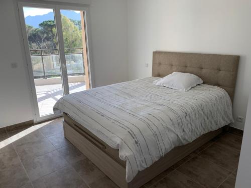 un letto in una camera da letto con una grande finestra di T2 neuf bord de plage - terrasse - CALVI a Calvi