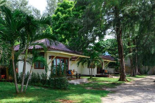 a small white house with palm trees in the yard at Wapi Resort in Ko Lipe