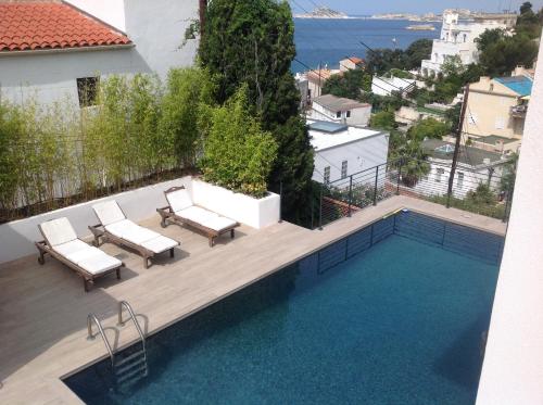 - une piscine avec 2 chaises longues à côté d'une maison dans l'établissement Suite sur la mer Marseille Corniche, à Marseille