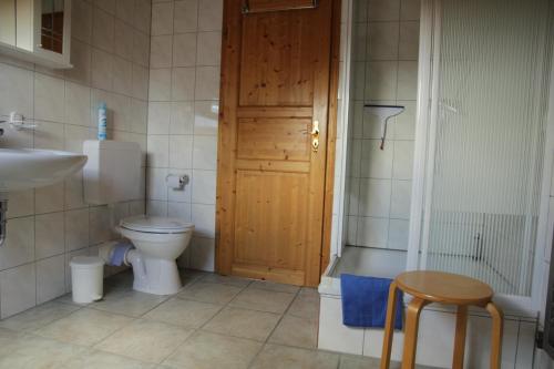 ein Badezimmer mit einem WC, einem Waschbecken und einer Holztür in der Unterkunft HAusZeit Kapitänshaus Friedrichsschleuse in Carolinensiel