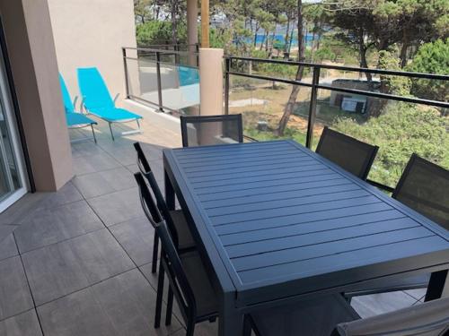 une table bleue et des chaises sur un balcon dans l'établissement T2 neuf bord de plage - terrasse - CALVI, à Calvi