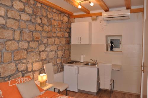 eine Küche mit einer Steinmauer sowie einem Tisch und Stühlen in der Unterkunft Apartments Lucic in Dubrovnik