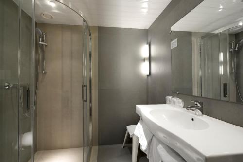 a bathroom with a shower and a sink and a mirror at Kyriad Montbeliard Sochaux in Montbéliard