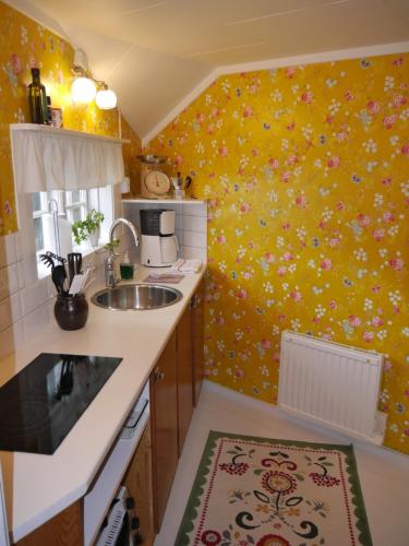 uma cozinha com um lavatório e uma parede amarela em Havsnära 1700-tals Timmerstuga em Ängelholm