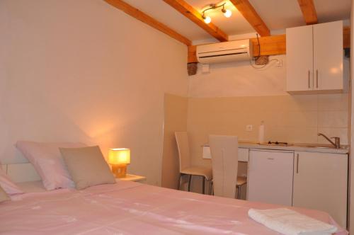 a bedroom with a white bed and a kitchen at Apartments Lucic in Dubrovnik