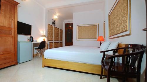 a bedroom with a white bed with a desk and a chair at Discovery Hotel in Hanoi