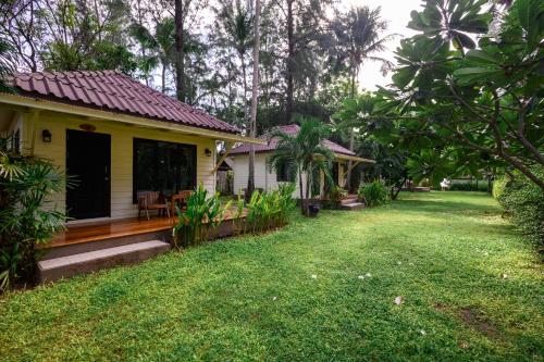 a small yellow house with a porch and a yard at Wapi Resort in Ko Lipe