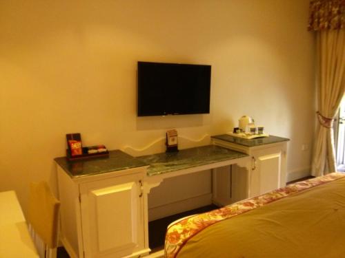 a room with a desk with a television on a wall at Welcomhotel by ITC Hotels, The Savoy, Mussoorie in Mussoorie