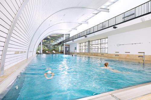 two people swimming in a large indoor swimming pool at Aspria Berlin Ku'damm in Berlin