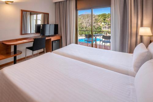 a hotel room with a bed and a desk and a window at Ciudad de Castelldefels in Castelldefels