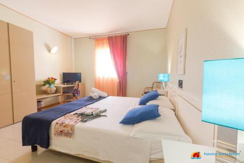 a bedroom with a large white bed with blue pillows at Hotel Paradise Beach Resort in Marinella di Selinunte