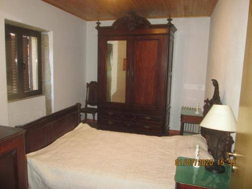 a bedroom with a bed with a dresser and a mirror at Pêssego - AL in Arouca