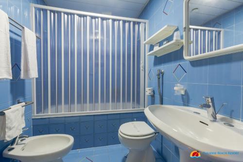 a blue bathroom with a toilet and a sink at Hotel Paradise Beach Resort in Marinella di Selinunte