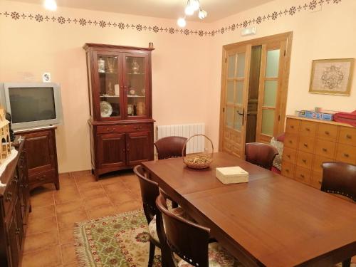 a dining room with a wooden table and a television at Hotel Rural Villa y Corte, Alojamientos Turísticos in Ampudia