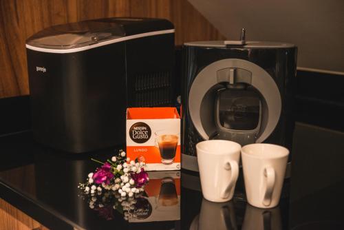 a coffee maker and two cups and flowers on a counter at Apartments Marconio Wellness Club in Belgrade