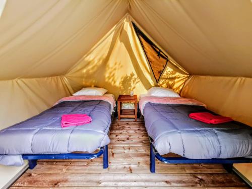 two beds in a canvas tent with a table at Les Tentes Bivouacs by Le Marintan in Saint-Michel-de-Maurienne