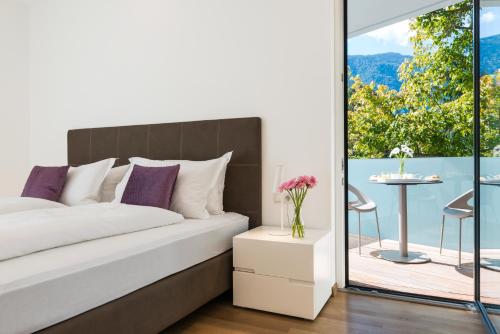 a bedroom with a bed and a balcony with a table at Residence Désirée Classic & Design in Merano
