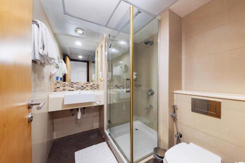 uma casa de banho com um chuveiro, um WC e um lavatório. em Citymax Sharjah em Sharjah