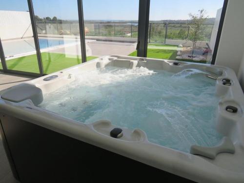 een groot bad in een kamer met een raam bij Villa Ria Alvor- Swimming pool & Jacuzzi in Alvor