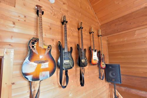 a row of guitars hanging on a wall with a speaker at Carrefour Guesthouse カルフール ゲストハウス in Yokamachi