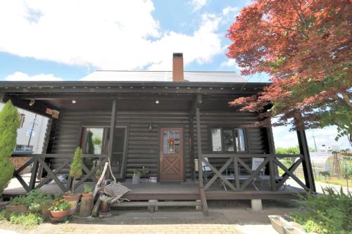 a small wooden cabin with a porch and a door at Carrefour Guesthouse カルフール ゲストハウス in Yokamachi