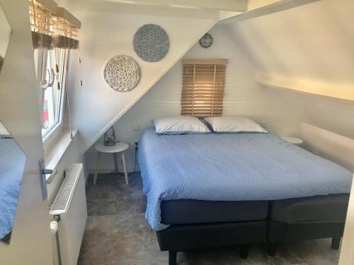 a bedroom with a blue bed in a attic at Ferienhaus Glücklich am Meer 1 mit Wellnesszugang in Egmond aan Zee