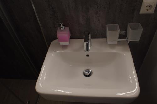a white sink in a bathroom with a pink candle at Hotel & Gasthaus Zum Eichenkranz in Luckenwalde