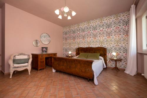 a bedroom with a large bed and a chair at Villa Barbara in Santa Luce