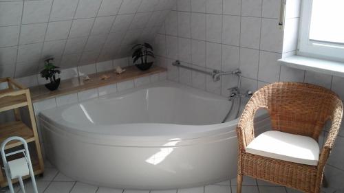 La salle de bains est pourvue d'une baignoire blanche et d'une chaise. dans l'établissement Pension Stahlberg, à Lübz