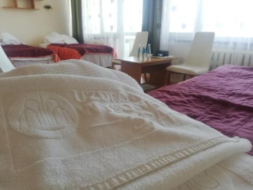 a bed with a white towel on top of it at Ośrodek Uzdrowiskowy Biawena in Wysowa-Zdrój
