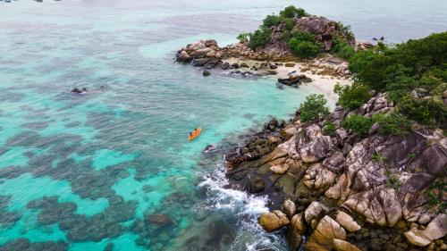 an aerial view of a rocky beach with people in the water at Wapi Resort in Ko Lipe