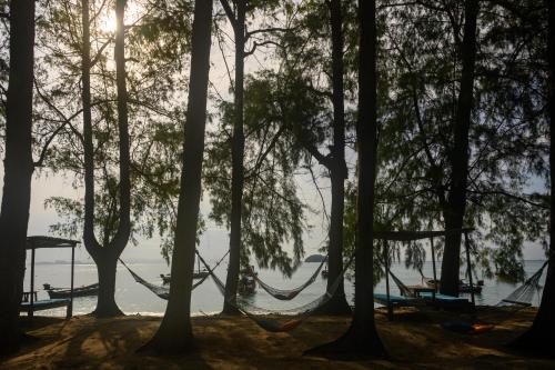 a group of trees with hammocks on the shore of a lake at Wapi Resort in Ko Lipe